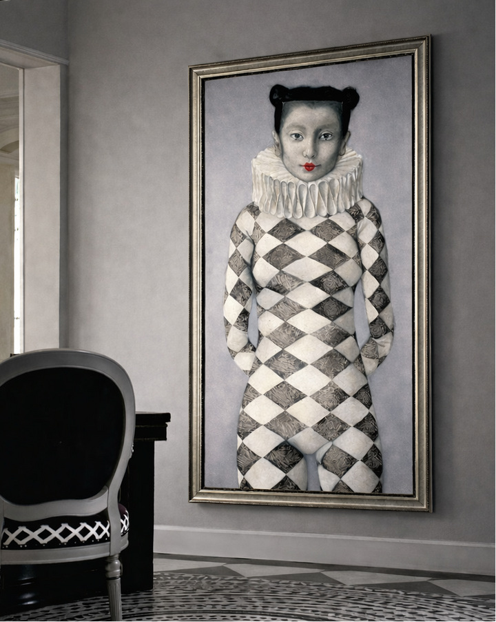 Framed artwork of a person in a patterned outfit on a wall in a room with a chair and lamp.