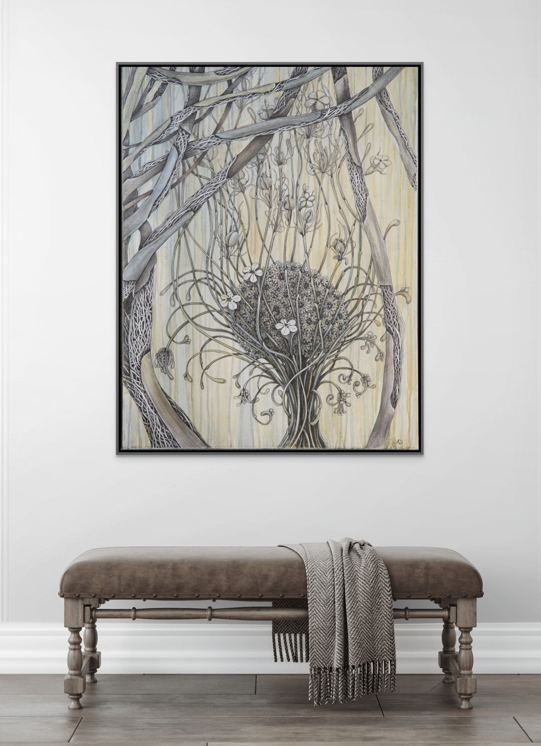 Framed artwork of a tree with a nest on a white wall above a wooden bench.