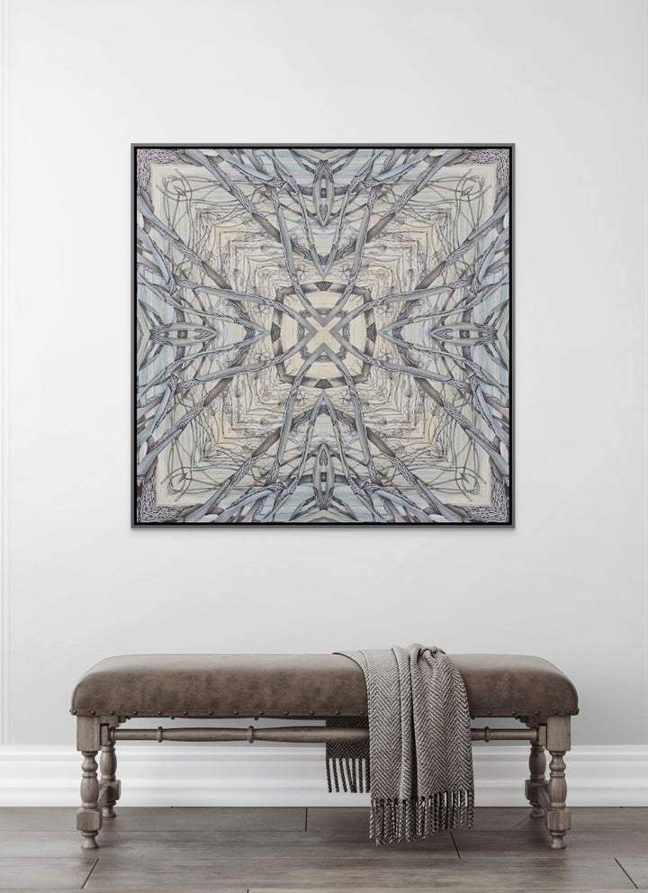 Framed abstract art piece on a white wall above a wooden bench with a blanket.