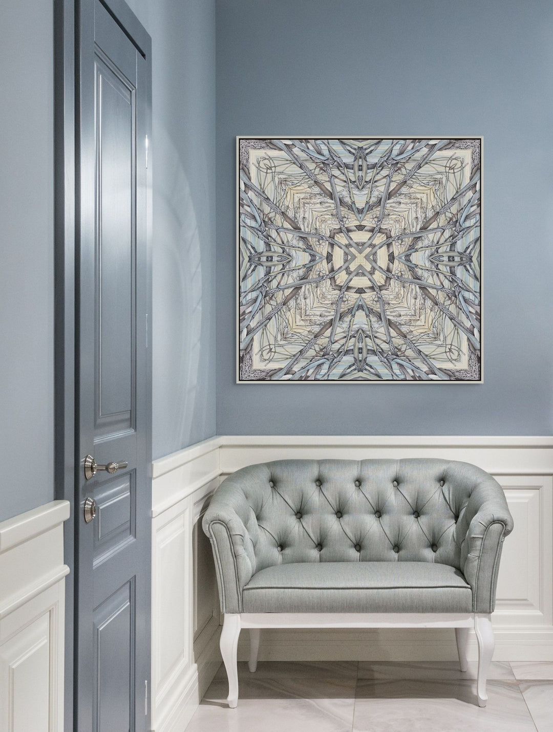 Gray tufted sofa in a room with a decorative wall painting on a blue wall.