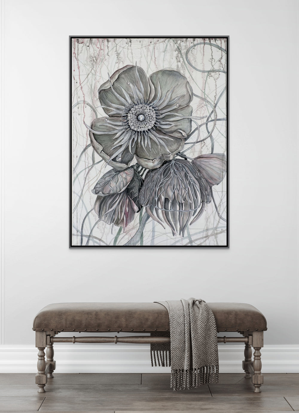 Framed floral artwork on a wall above a bench with a blanket.