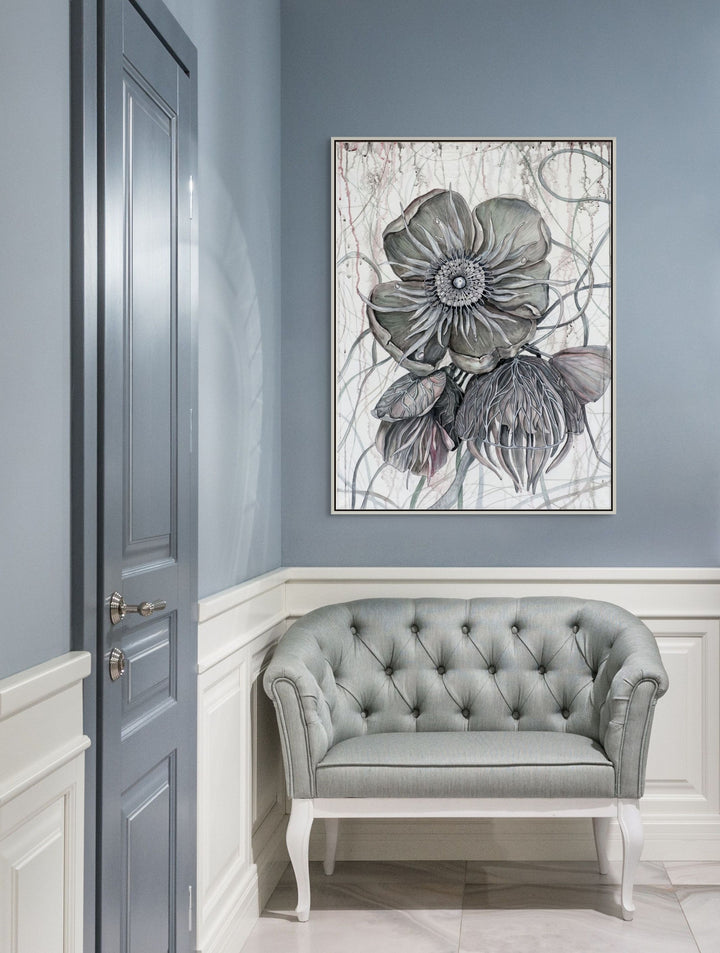 Gray tufted sofa in a room with a floral artwork on the wall.
