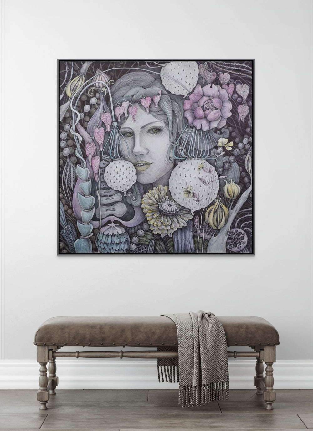 Framed artwork of a woman with floral elements on a white wall above a wooden bench.