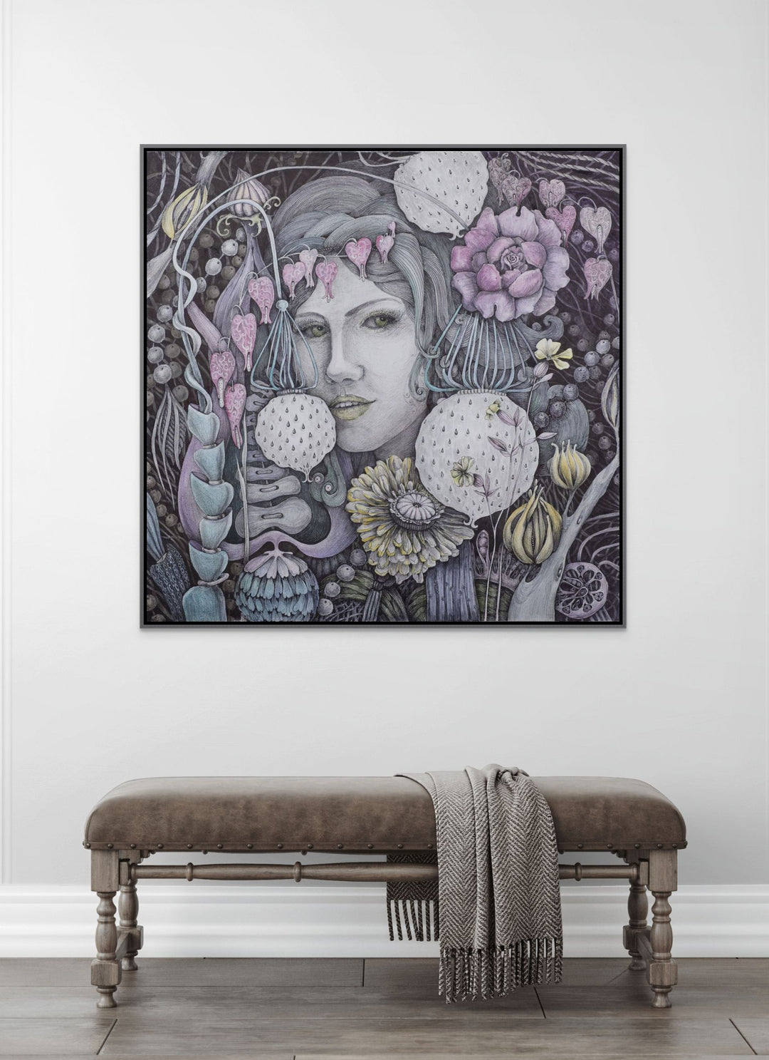 Framed artwork of a woman with floral elements on a white wall above a wooden bench.