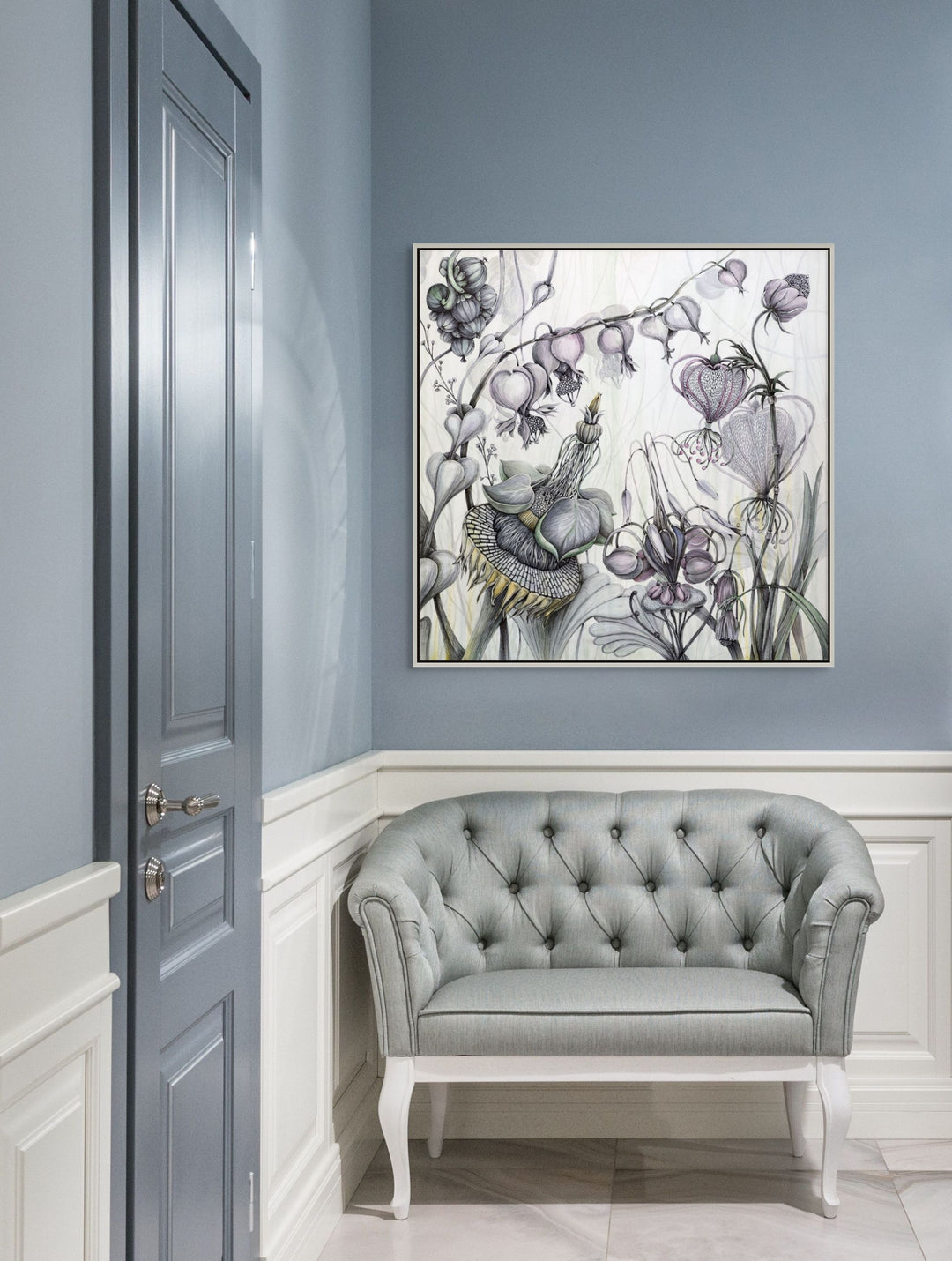 Decorative painting on a wall above a gray tufted sofa in a room with light blue walls.