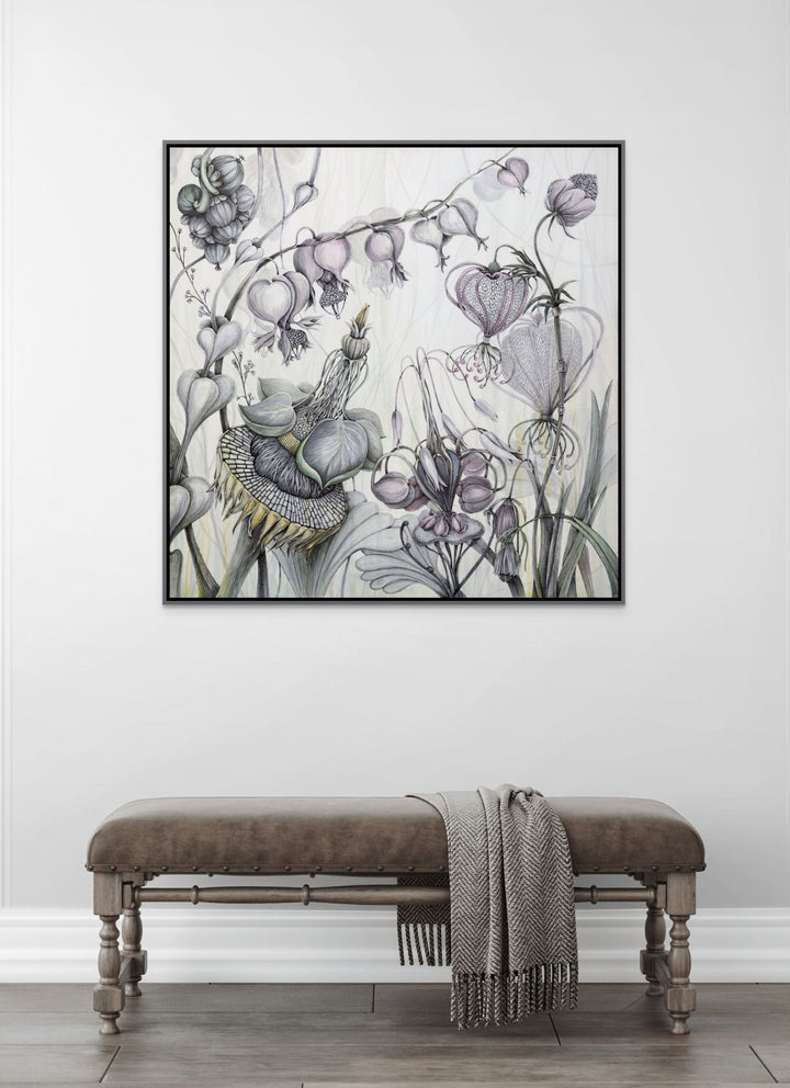 Framed botanical artwork on a wall above a wooden bench with a blanket.