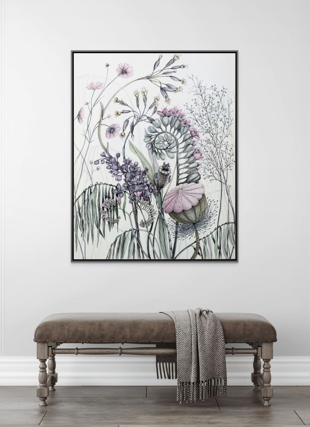 Framed floral artwork on a wall above a bench with a blanket.