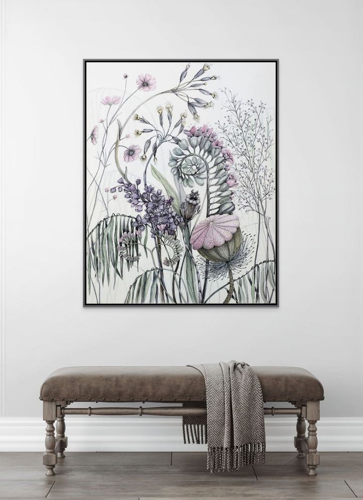 Framed floral artwork on a wall above a bench with a blanket.