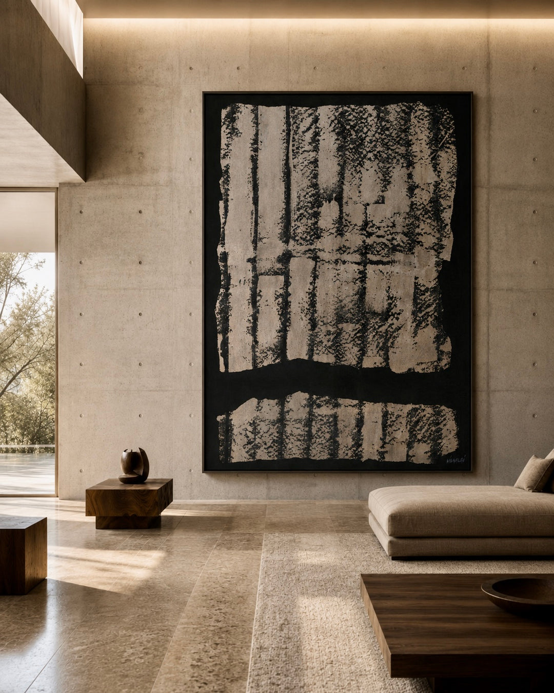A large framed abstract black and off-white artwork hangs on a concrete wall in a modern minimalist living room with a beige sofa, wooden tables, and warm ambient lighting.