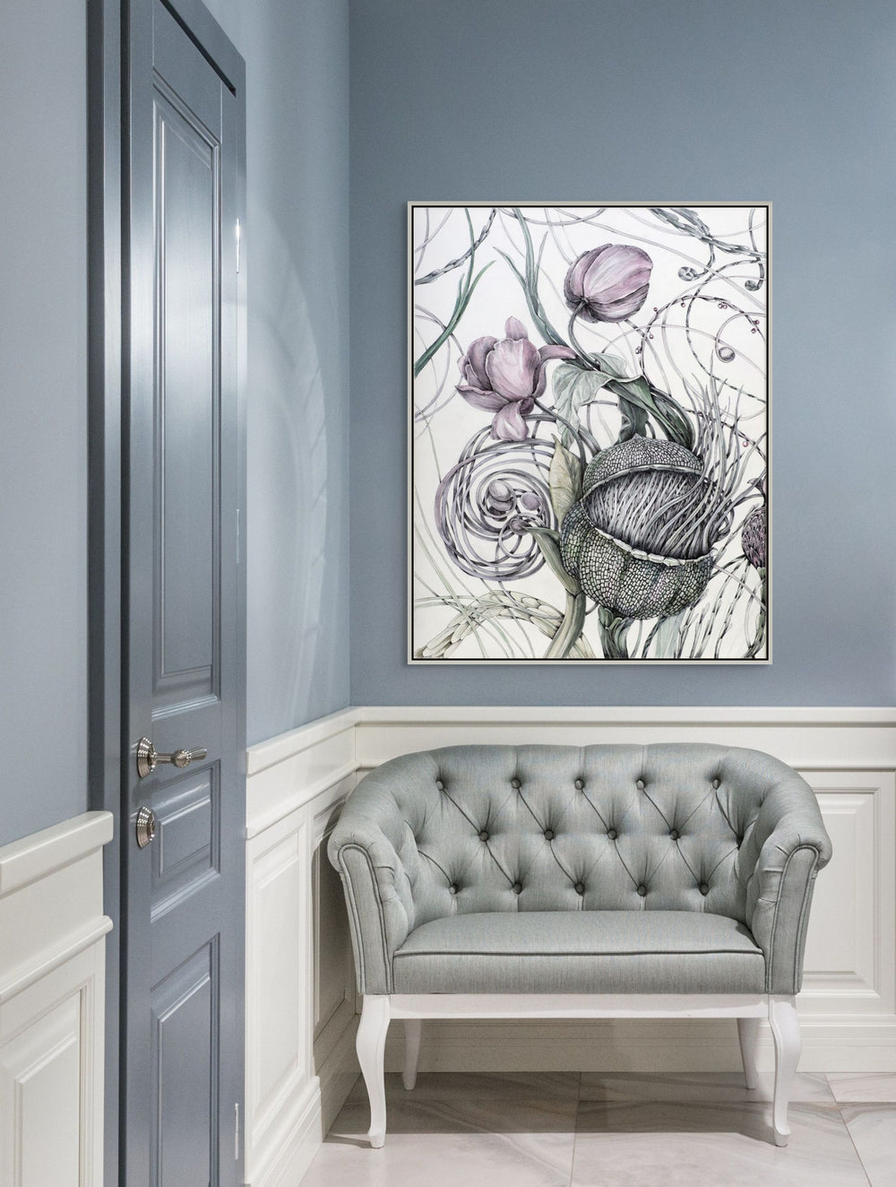 Decorative floral painting on a wall above a gray tufted sofa in a room with light blue walls.
