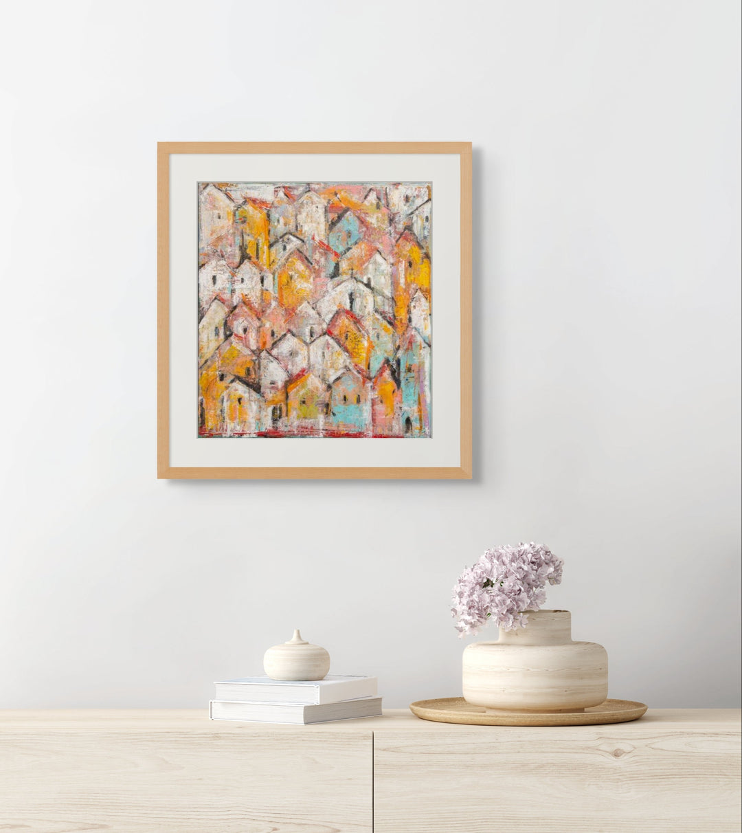 Framed abstract art piece on a white wall above a wooden cabinet with decorative items.