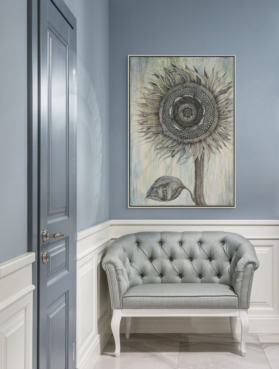 Gray tufted sofa in a room with a sunflower painting on the wall.